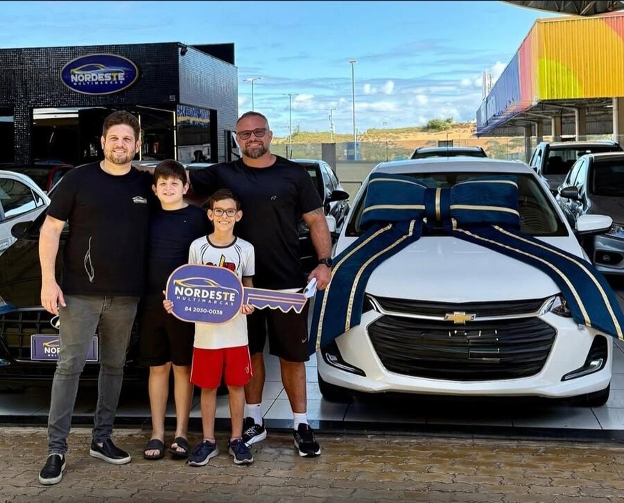 Cliente da +Rating com a família na loja de veículos, recebendo a chave do carro branco
